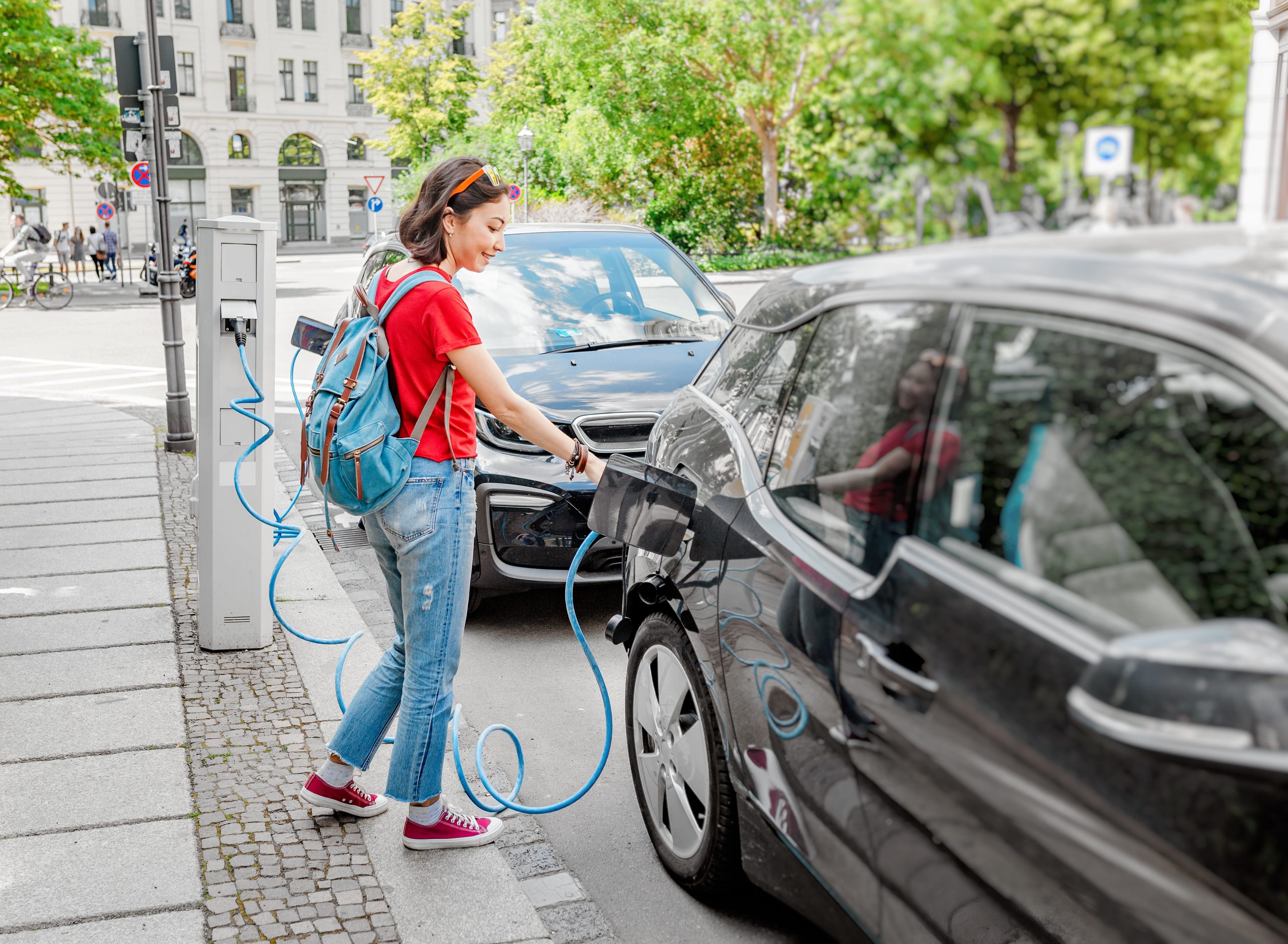 Man charging electric car while holding smartphone